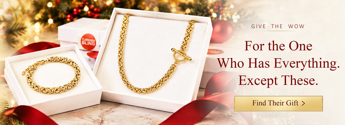 Gold Byzantine chain necklace with a toggle clasp in a Turkish Bling gift box, among holiday pine and red ribbon.