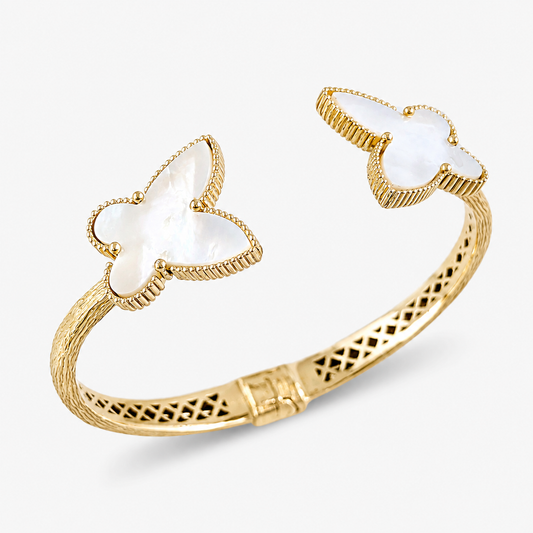 A gold-toned open cuff bangle bracelet featuring two butterfly-shaped inlays of milky white mother-of-pearl, shown on a light gray background.