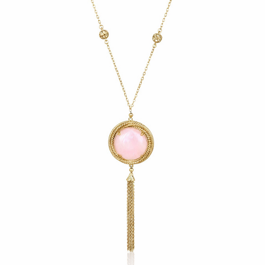 A gold-toned necklace featuring a circular pendant with a pale pink stone, surrounded by a textured gold border, with a dangling chain tassel below.
